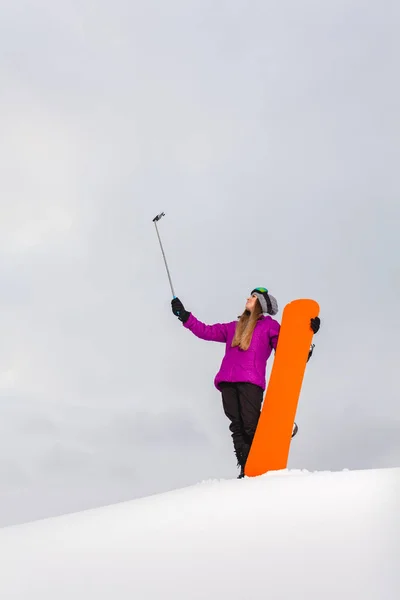 Junge Frau mit dem Snowboard schießt ein Selfie mit ihrem Handy — Stockfoto