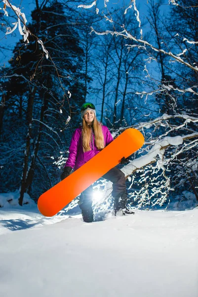 Junge sexy Frau mit ihrem Snowboard im dunklen Winterwald — Stockfoto