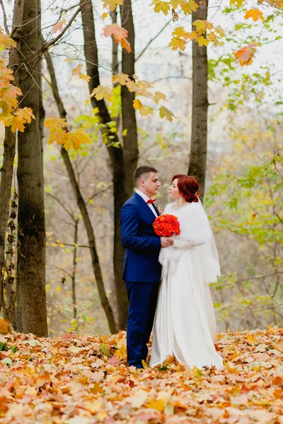 Braut und Bräutigam im Herbstpark und fliegendes Herbstlaub — Stockfoto