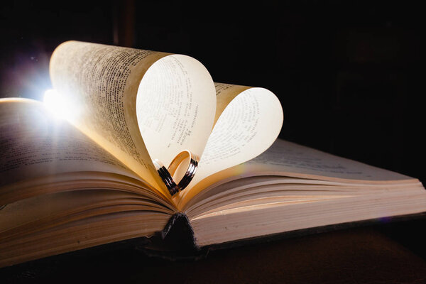 Wedding rings and the book in the rays of bright light