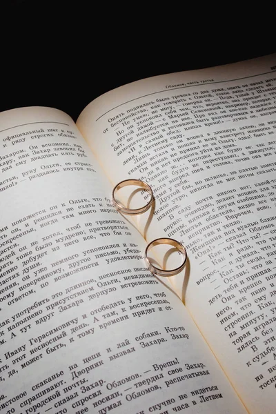 Anillos de boda y el libro en los rayos de luz brillante — Foto de Stock