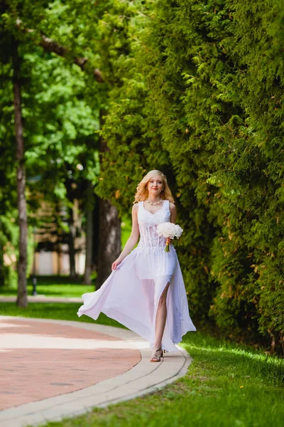 Jonge mooie bruid in witte jurk is wandelen in het park van de zomer — Stockfoto