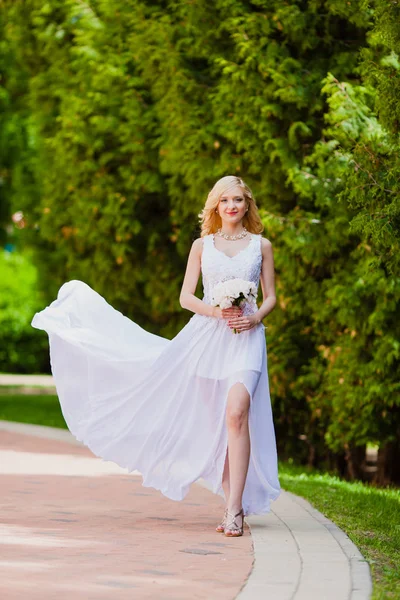 Jonge mooie bruid in witte jurk is wandelen in het park van de zomer — Stockfoto