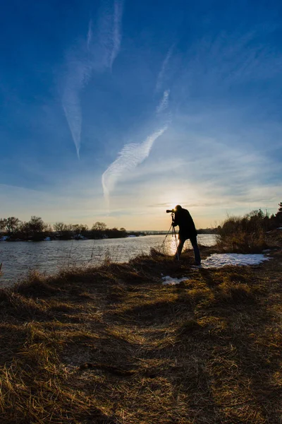 Професійний фотограф, який фотографує затоплену річку на заході сонця — стокове фото