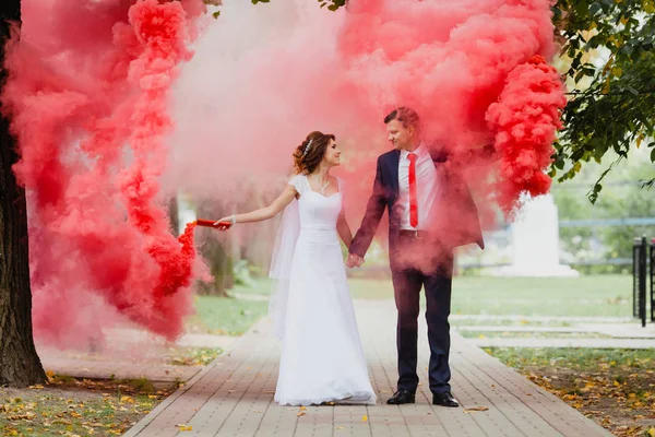 Noiva e noivo com a fumaça de cor vermelha — Fotografia de Stock
