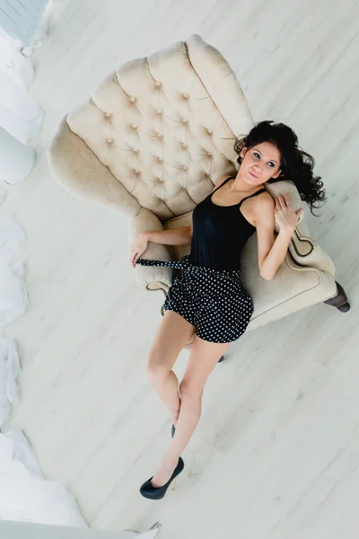 Slender brunette lying on a white armchair — Stock Image Slender brunette lying on a white armchair Royalty Free Stock Photos