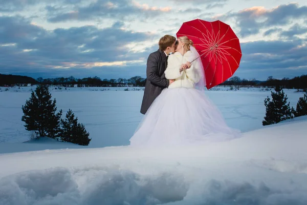 Νύφη και ο γαμπρός με μεγάλη κόκκινη ομπρέλα — Φωτογραφία Αρχείου