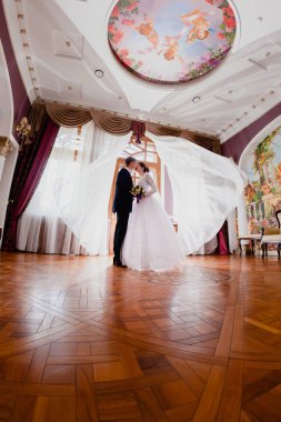 Düğün çifti ve havada uçan perdeler