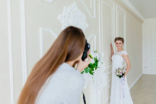 Фотограф фотографирует молодую сексуальную невесту в студии — стоковое фото