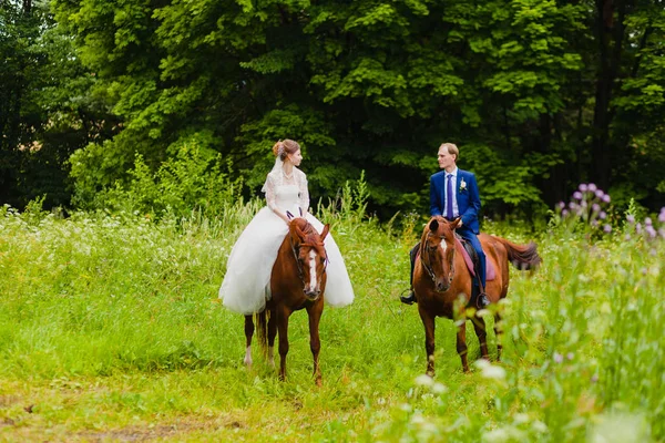 Beaux jeunes mariés chevauchant deux chevaux — Photo