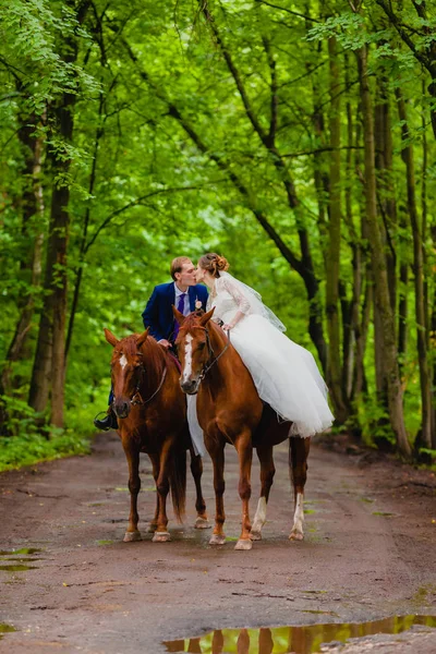 Mooie jonggehuwden rijden twee paarden — Stockfoto