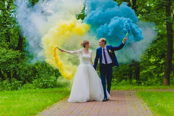 Bride and groom with colorful smoke bombs — Stock Photo, Image