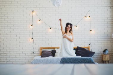 Büyük bir yatağa oturmuş komik ince esmer