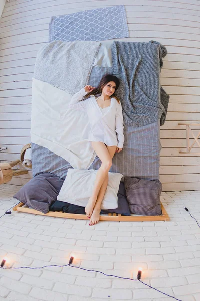 Sexy slender brunette lying on a big bed — Stock Image Sexy slender brunette lying on a big bed Stock Photo