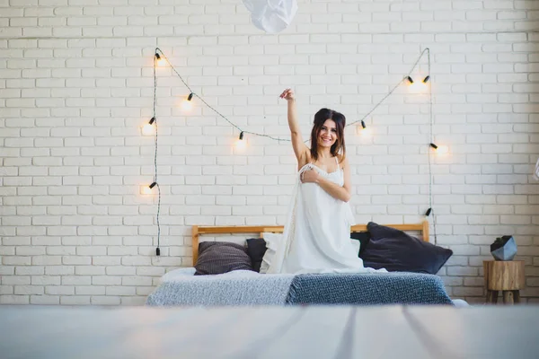 Funny slender brunette sitting on a big bed — Stock Image Funny slender brunette sitting on a big bed Royalty Free Stock Photos