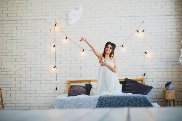 Funny slender brunette sitting on a big bed — Stock Image Funny slender brunette sitting on a big bed Stock Image