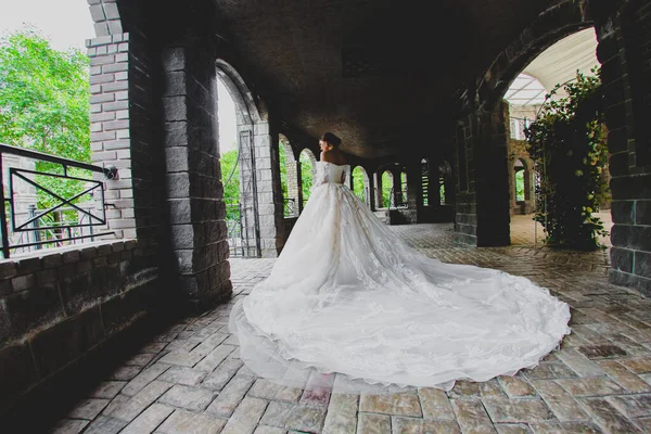 Jeune belle mariée en robe de luxe avec un long train posant dans un hôtel de campagne — Photo