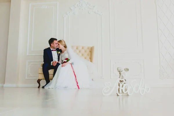 Mariée assise sur un canapé blanc dans le grand hall blanc — Photo