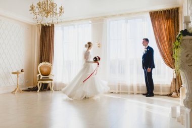 Damat, gelininin büyük pencerenin yanında nasıl dans ettiğini izliyor.