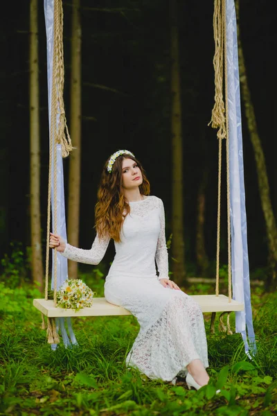 Retrato de la hermosa novia joven sentada en el columpio de cuerda — Foto de Stock