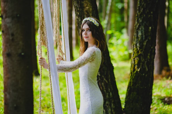 Hermosa joven novia posando cerca del columpio de cuerda —  Fotos de Stock