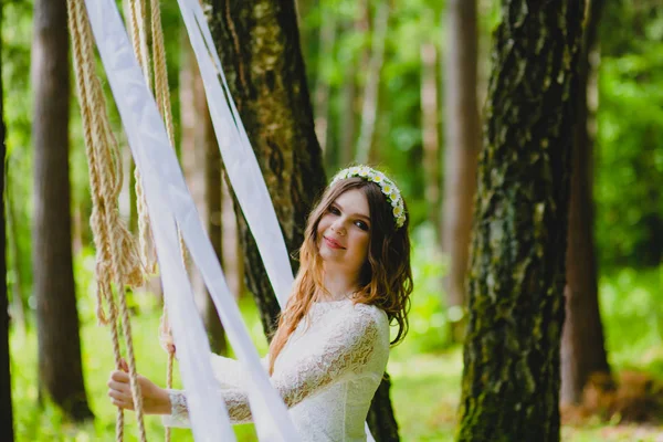 Hermosa joven novia posando cerca del columpio de cuerda — Foto de Stock