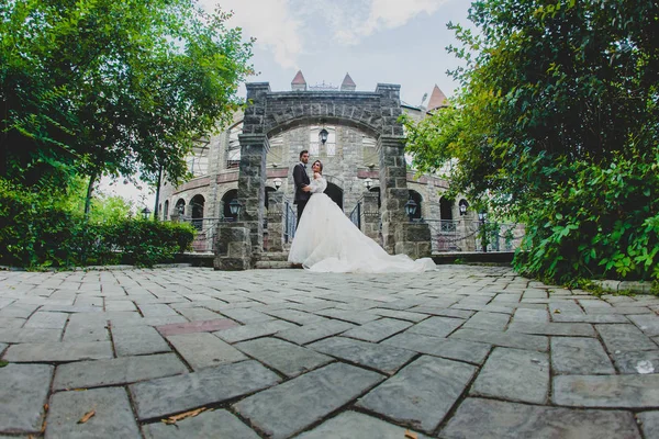 Couple image grand angle de jeunes mariés élégants debout près de l'arche — Photo