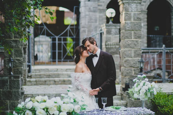 Belo casal de recém-casados estão posando perto da mesa decorada elegante — Fotografia de Stock