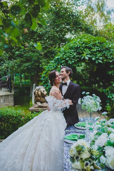 Skrattande par nygifta nära det eleganta dekorerade bordet — Stockfoto