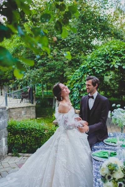 Couple riant de jeunes mariés près de la table décorée élégante — Photo