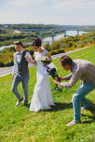 Fotógrafo de casamento tirando fotos da noiva e do noivo em uma encosta — Fotografia de Stock