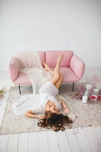 Ung brud med vackra nakna ben poserar på ett golv i den stora vita studion — Stockfoto