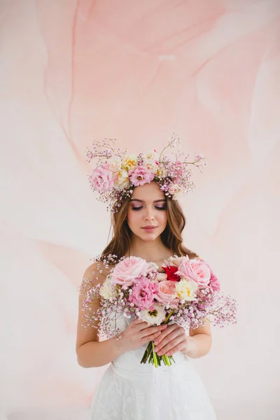 Porträtt av vacker brud med blomsterkrans på huvudet och brudbukett Stockbild