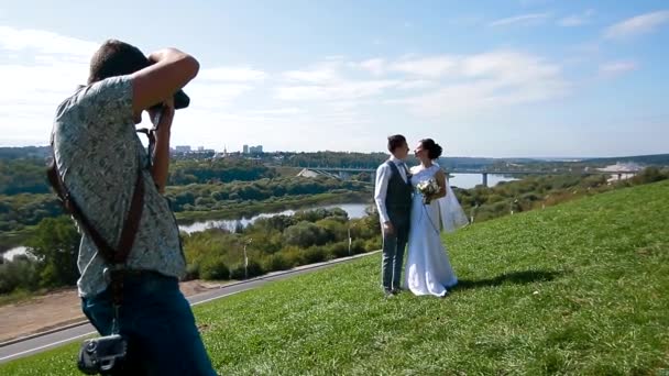 Bröllopsfotograf tar bilder på bruden och brudgummen på en bergssluttning — Stockvideo