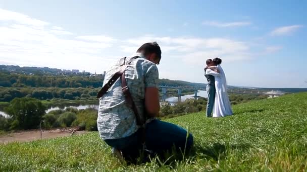 Bröllopsfotograf tar bilder på bruden och brudgummen på en bergssluttning — Stockvideo