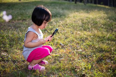 Asyalı Çinli küçük kız olan büyüteç keşfetmek