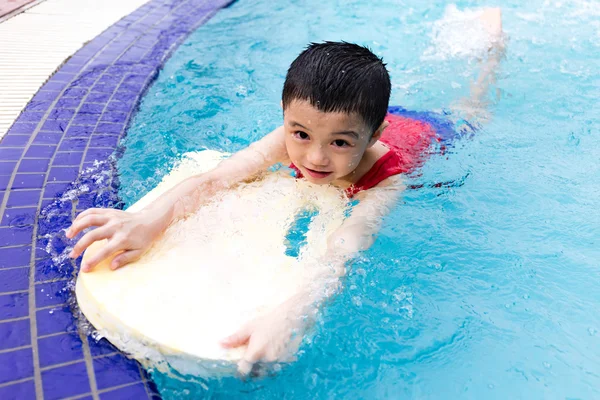 Asiatiska kinesiska lilla pojke simning med flytande styrelse — Stockfoto