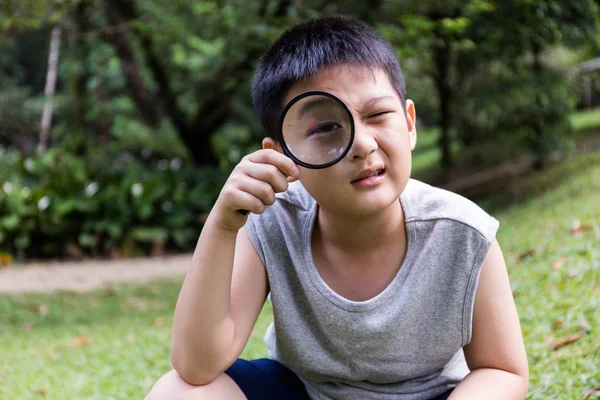 Счастливый азиатский китайский мальчик смотрит через лупу — стоковое фото