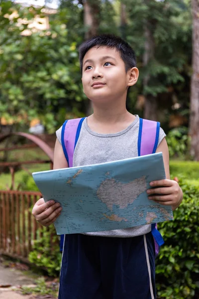 Asian Chinese little boy holding map in the forest