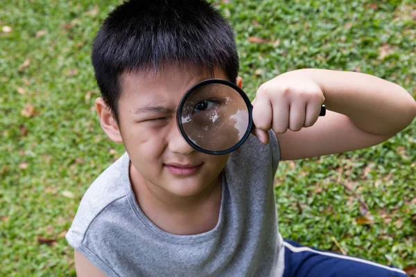 Glücklich asiatische chinesische kleine Junge suchen durch Lupe — Stockfoto