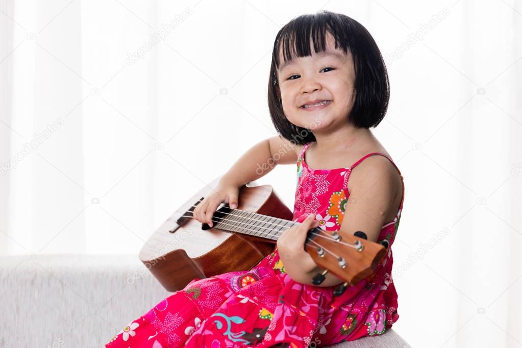 Happy Asian Chinese little girl playing ukele