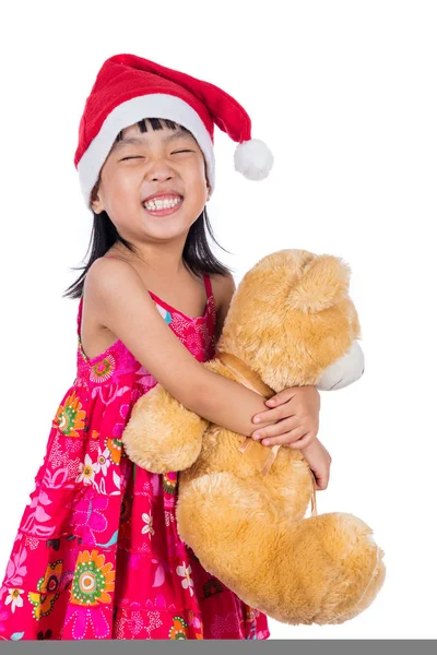 Азиатская маленькая девочка в шляпе Санты с плюшевым мишкой — стоковое фото