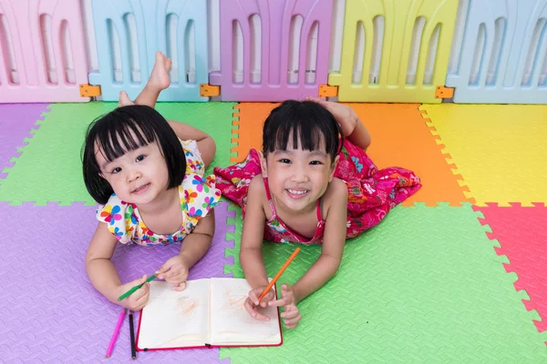 Feliz asiática china hermanitas tendidas en el suelo para colorear —  Fotos de Stock