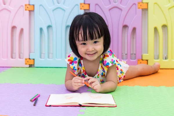 Happy Asian Chinese little girl laying on the floor coloring — Stock Photo, Image