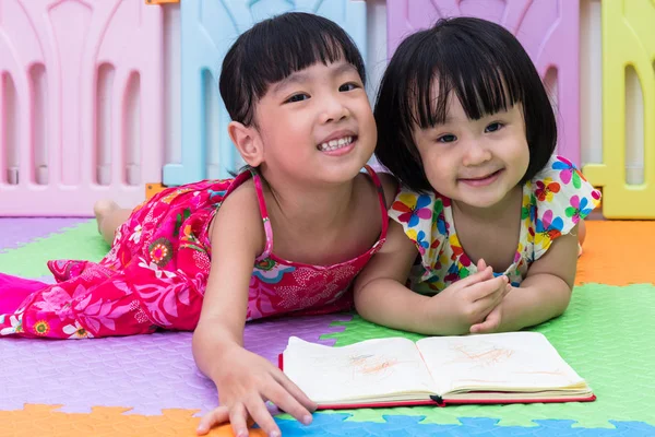 Asiatique chinois petites sœurs couché sur le sol lecture — Photo