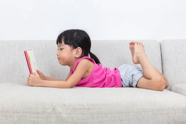 Asiático chinês menina deitado no sofá com livro — Fotografia de Stock