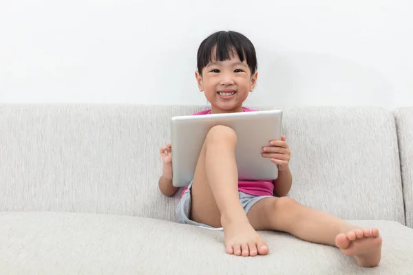 Feliz asiática china niña sentada en sofá con la tableta — Foto de Stock