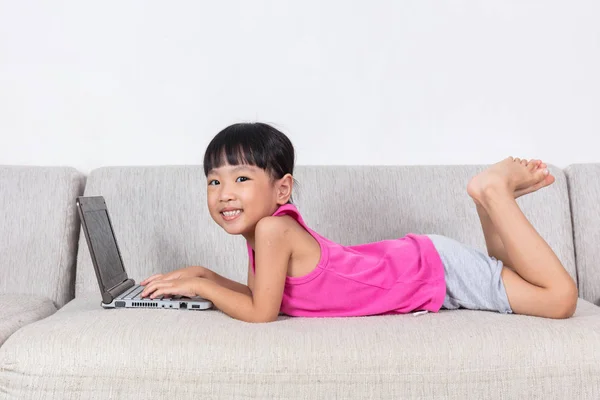 Sonriente asiática niña china acostada en el sofá utilizando el ordenador portátil — Foto de Stock