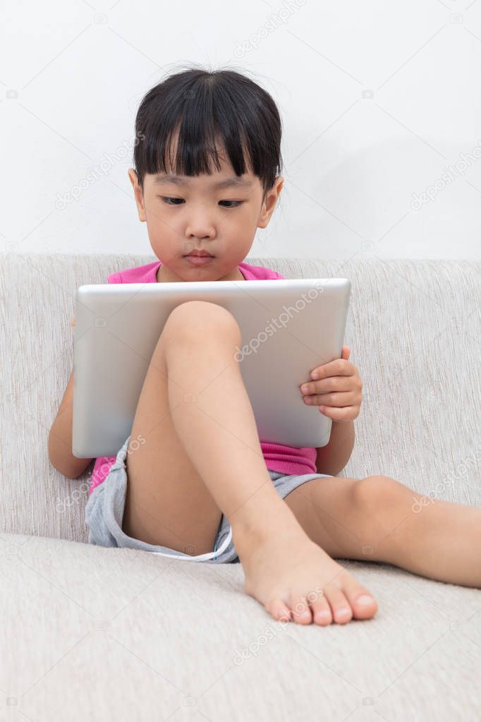 Asian Chinese little girl sitting on the sofa with tablet