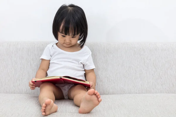 Ασίας κινεζική μικρό κορίτσι που κάθεται στον καναπέ με βιβλίο — Φωτογραφία Αρχείου